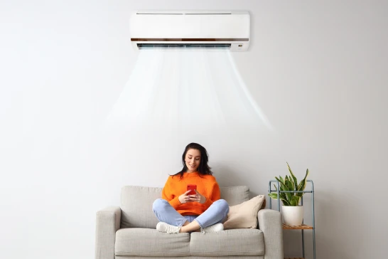 Kobieta siedząca pod klimatyzatorem